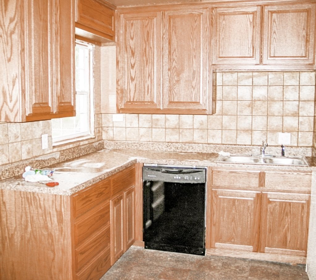 Modern kitchen interior with light wood cabinetry, a stainless steel oven and cooktop, and a white tile backsplash.