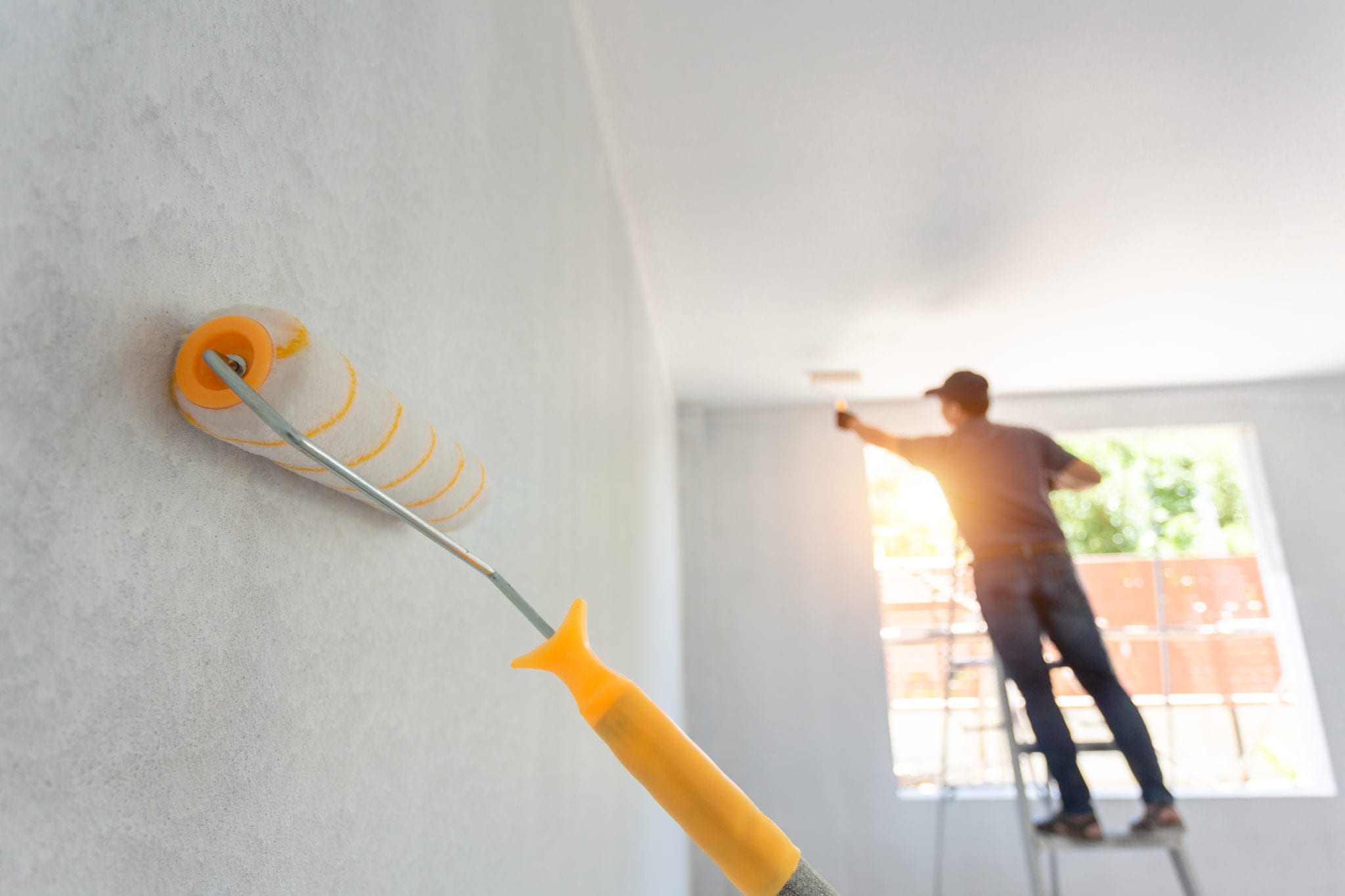 Interior Painting Roller and the Worker in the Background. Home Remodeling Concept.